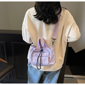 Détail du sac seau en toile violette avec cordon de serrage et bandoulière réglable