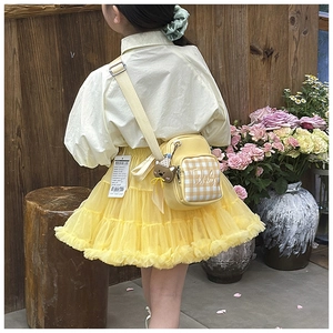 Detail of yellow plaid crossbody bag with a cute brown bear pendant on a kids outfit