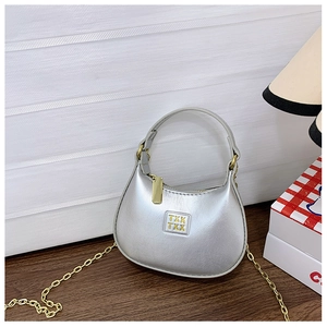 Détail d'un mini sac à main demi-lune argenté avec chaîne dorée sur surface en bois