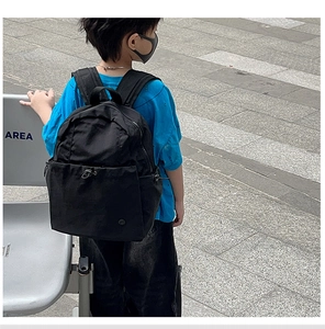 Outdoor shot of a black ergonomic backpack showing a spacious front bungee cord pocket