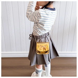 Détail d'un mini sac doré métallisé pour enfant avec nœud et bandoulière sur une petite fille