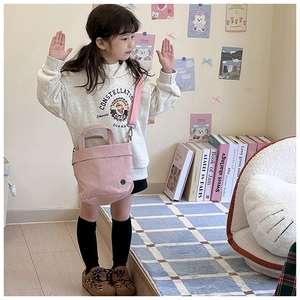 Close-up of pink canvas bag for kids featuring a minimalist logo and adjustable shoulder strap