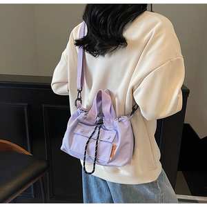 Détail du sac seau en toile lilas avec cordon de serrage, poche avant et étiquette orange