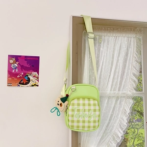 Detail of light green checkered kids crossbody bag featuring a cute plush bear charm