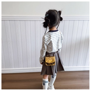 Vue arrière d'un enfant portant le sac bandoulière doré métallisé avec nœud et chaîne