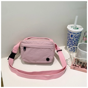 Detail of pink canvas kids crossbody bag featuring adjustable strap and front zipper pocket