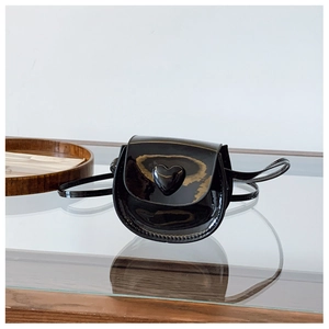 Detail of mini black patent leather heart-shaped bag with glossy finish and strap