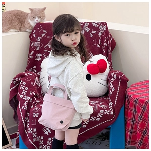 Pink toddler crossbody bag shown with adjustable strap in a cozy lifestyle setting
