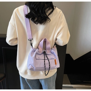 Détail du sac seau en nylon violet clair avec étiquette orange et sangle à cordon contrasté