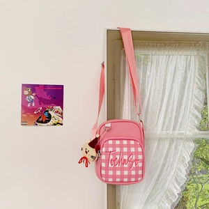 Detailed view of pink plaid crossbody bag with cute cat plush charm and embroidery