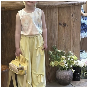 Detail of yellow checkered handbag with bear charm on girl in cotton tank top and pants