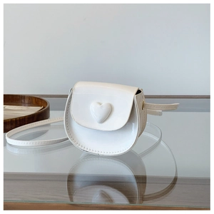 Detailed view of white patent leather heart crossbody bag with gold hardware and mirror reflection