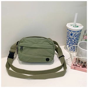 Detail of army green nylon crossbody bag showing smooth zippers and sturdy woven strap
