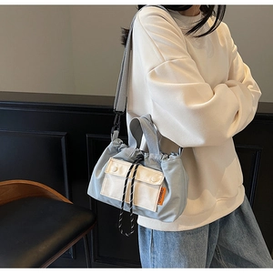 Détail du sac seau bleu avec poche crème et étiquette de marque orange vibrante