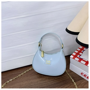 Détail d'un sac demi-lune en cuir bleu clair avec chaîne dorée et fermeture éclair sur bois