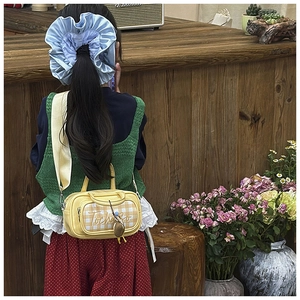 Detail showing a yellow checkered crossbody bag and blue oversized scrunchie on a child