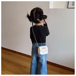 Détail d'un sac bandoulière blanc pour enfant avec boucle nœud doré et bandoulière chaîne