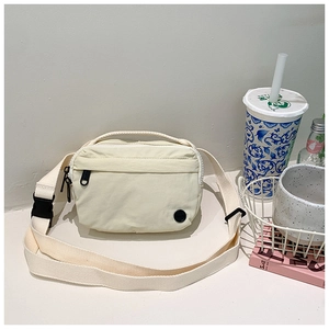 Close-up of cream canvas kids crossbody bag with black zipper and adjustable strap