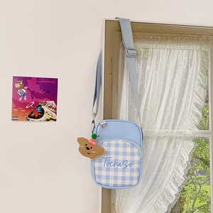 Detail of light blue kids crossbody bag with plaid pocket and plush bear pendant