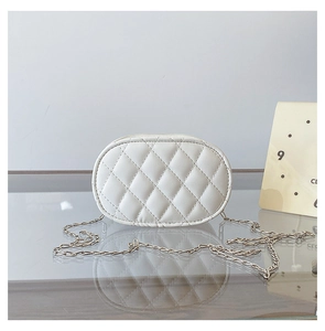 Close-up of white oval crossbody bag with quilted diamond pattern and gold chain strap