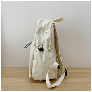 Side view of cream school backpack showing waterproof nylon fabric and side pocket detail