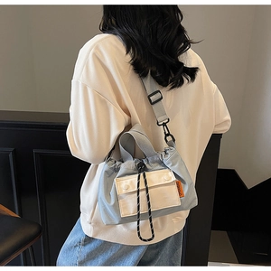 Détail du sac seau bleu clair avec cordon de serrage et bandoulière en tissu gris réglable