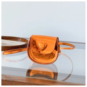 Detail of a shiny orange heart-shaped mini bag with metallic patent leather finish