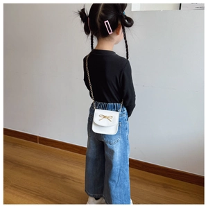 Détail du mini sac bandoulière blanc avec nœud doré et fine bandoulière chaîne