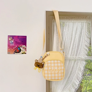 Detail of yellow plaid kids crossbody bag with a cute brown plush bear keychain charm