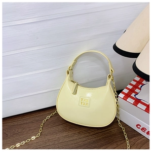 Détail du sac demi-lune jaune avec bandoulière chaîne dorée sur bureau en bois
