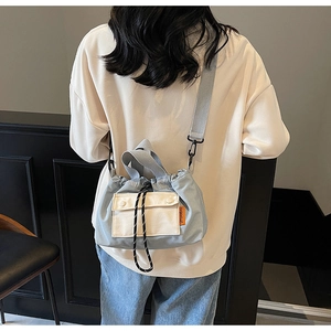 Détail du sac seau bleu clair à cordon avec poche à rabat et bandoulière réglable