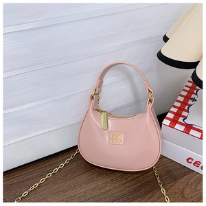 Détail du mini sac hobo rose clair avec chaîne dorée sur une surface en bois