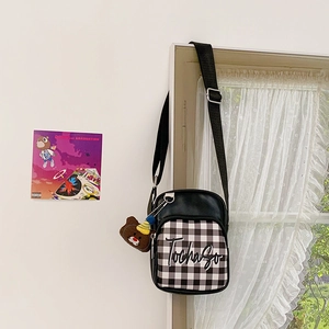 Detail of checkered kids crossbody bag with a cute brown teddy bear plush keychain