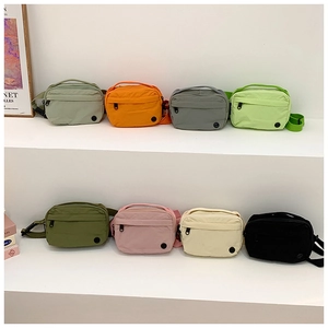 Kids nylon crossbody bags in eight vibrant colors displayed on white pedestals