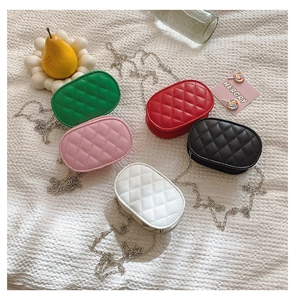 Flat lay of colorful oval quilted chain bags for kids in green red pink black and white