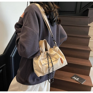 Détail du sac seau en toile beige avec cordon de serrage, poche pression et étiquette