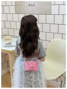Rear view of a child wearing the pink glitter mini chain crossbody box bag in a lifestyle setting