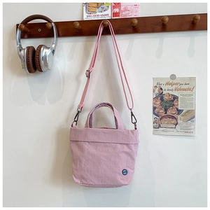 Detailed view of a pink fabric kids shoulder bag with adjustable strap and carry handle