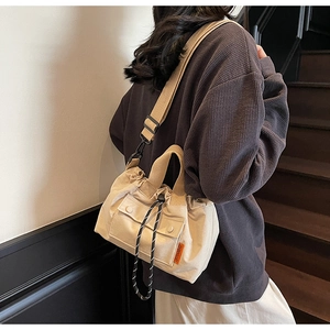 Détail du sac seau en toile beige avec cordon de serrage et bandoulière noire réglable