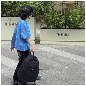 Detailed outdoor view of a black large capacity nylon school backpack on a child model