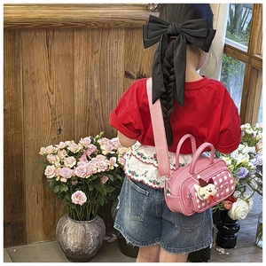Detail of pink plaid kids boston bag with cute cat charm and removable wide strap