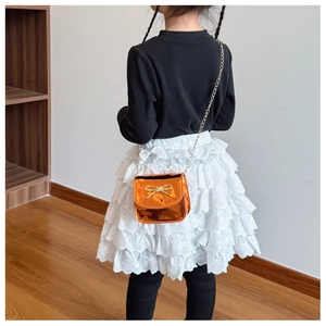 Détail du sac bandoulière bronze pour fille avec nœud perlé sur un mannequin enfant