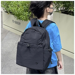 Outdoor shot of a black minimalist school backpack with multiple pockets and drawstrings