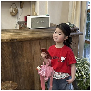 Close-up of a girl wearing a red Hello Kitty t-shirt with a pink checkered crossbody bag