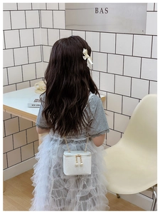 Close-up of white glitter kids crossbody bag featuring large pearl zipper charms and gold chain