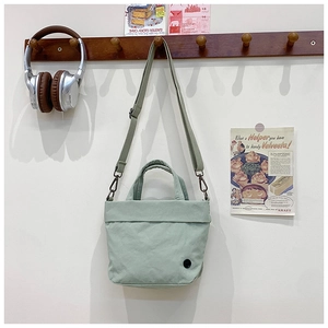 Detail of mint green canvas kids crossbody bag with adjustable strap and top handle
