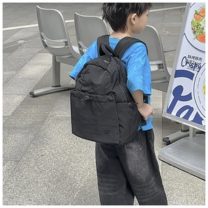 Close-up of black school backpack featuring a functional drawstring front pocket and matte fabric