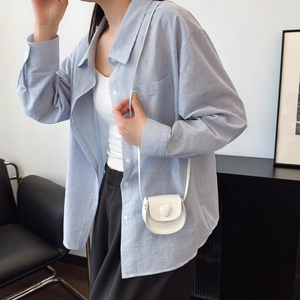 Chic light blue striped oversized shirt paired with a white heart-shaped mini crossbody bag