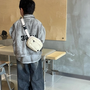 Child wearing cream canvas crossbody bag with adjustable strap in urban setting