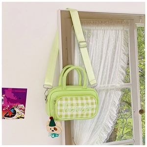 Detail of light green checkered kids handbag with cute bear pendant and wide strap